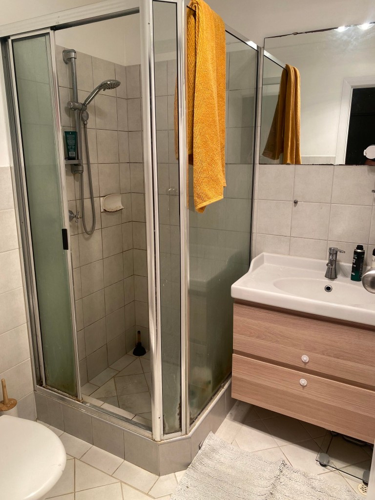 compact 2x2 bathroom layout with corner shower and storage